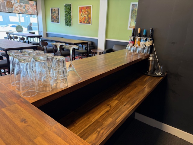 Timber bar top with upturned wine glasses and bottles of spirits