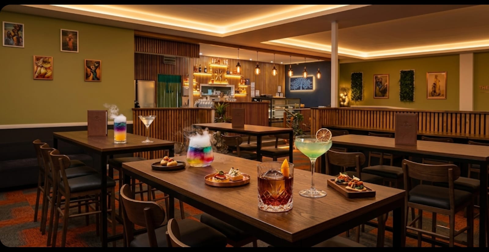 The fully licenced bar at Little Spicy with warm cove lighting, cocktails on wooden tables and a view of the bar counter