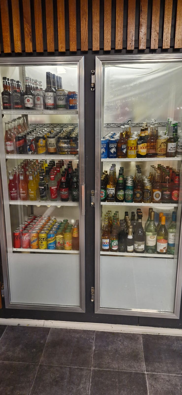 Tall double-door bottle fridge stocked with beers, wines and mixers